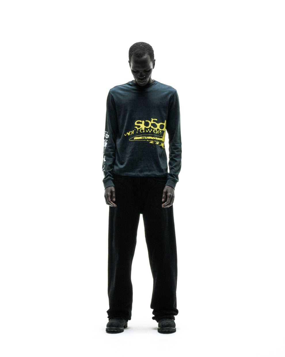 Black 100% cotton long sleeve tee with yellow "sp5d worldwide" graphic print on chest and sleeves.