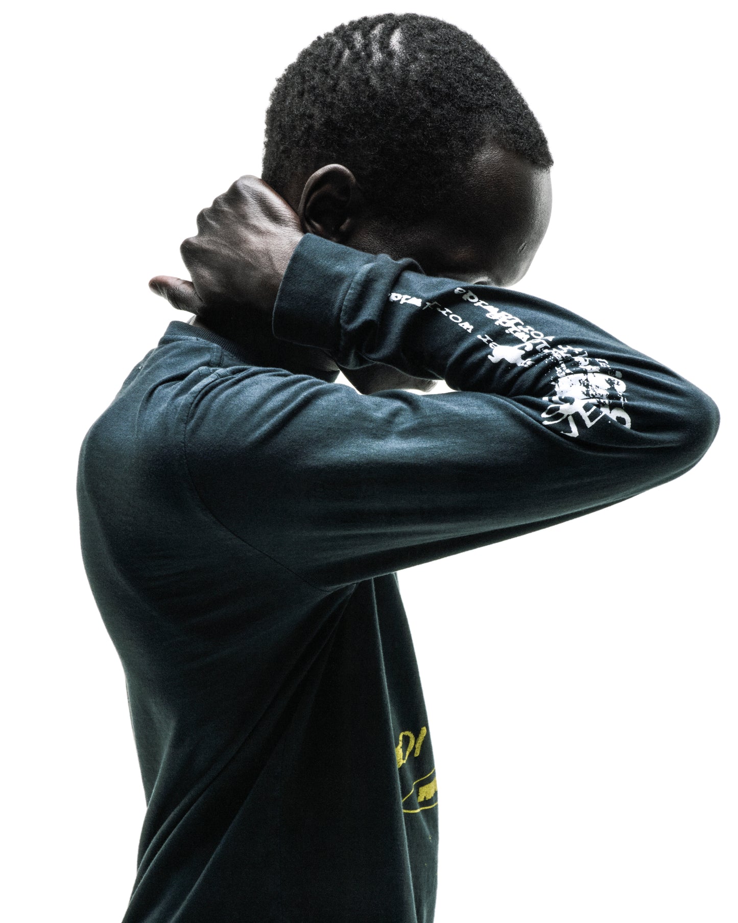 Dark-skinned person wearing a black 100% cotton long sleeve tee with white graphic prints on sleeves.