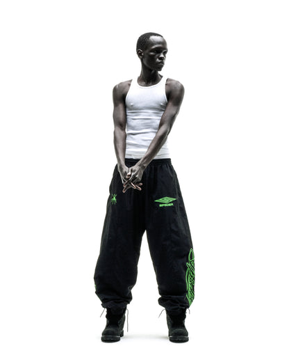 Black nylon track pants with green embroidered graphics, elastic cuffs, and drawstring waist.