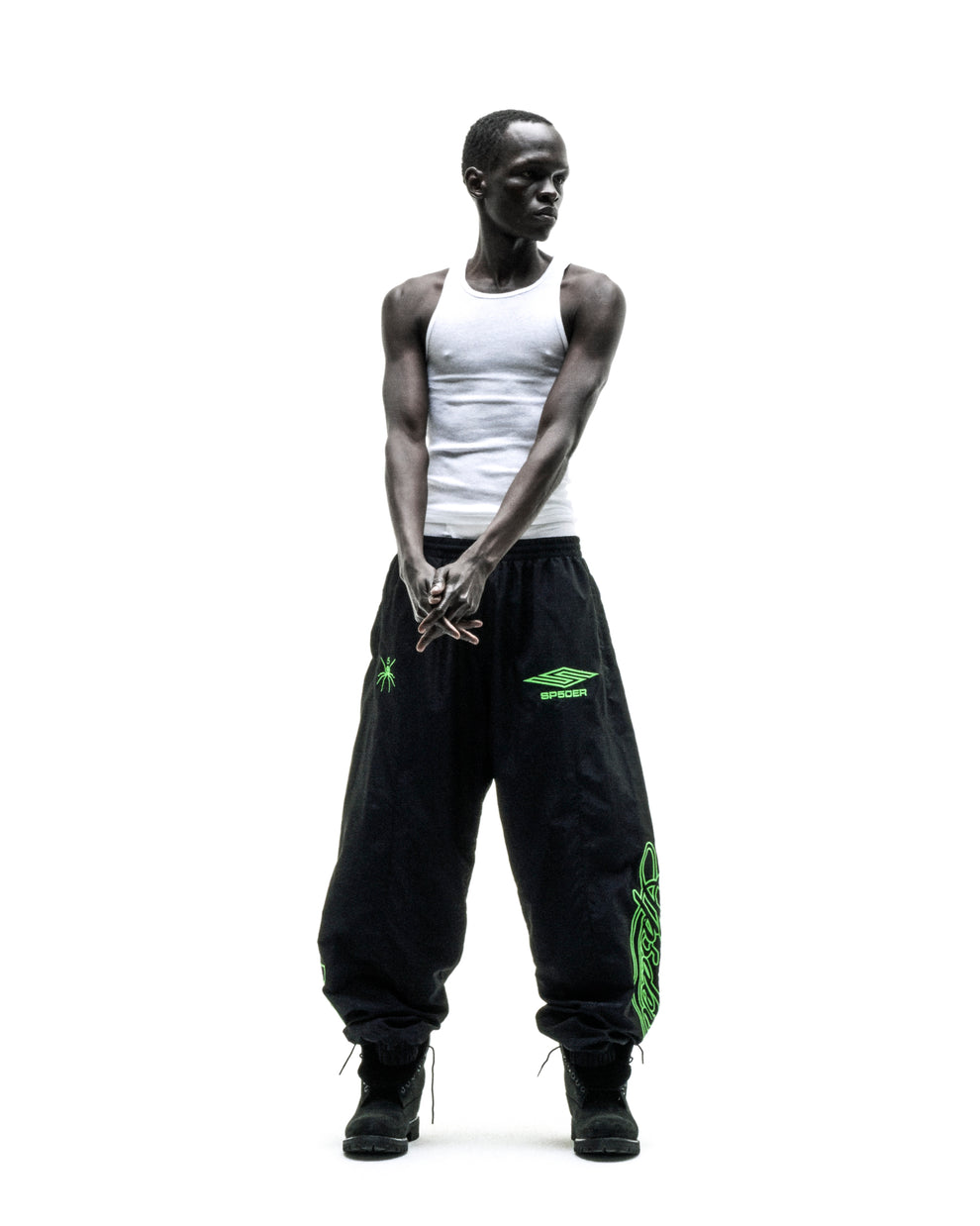 Black nylon track pants with green embroidered graphics, elastic cuffs, and drawstring waist.