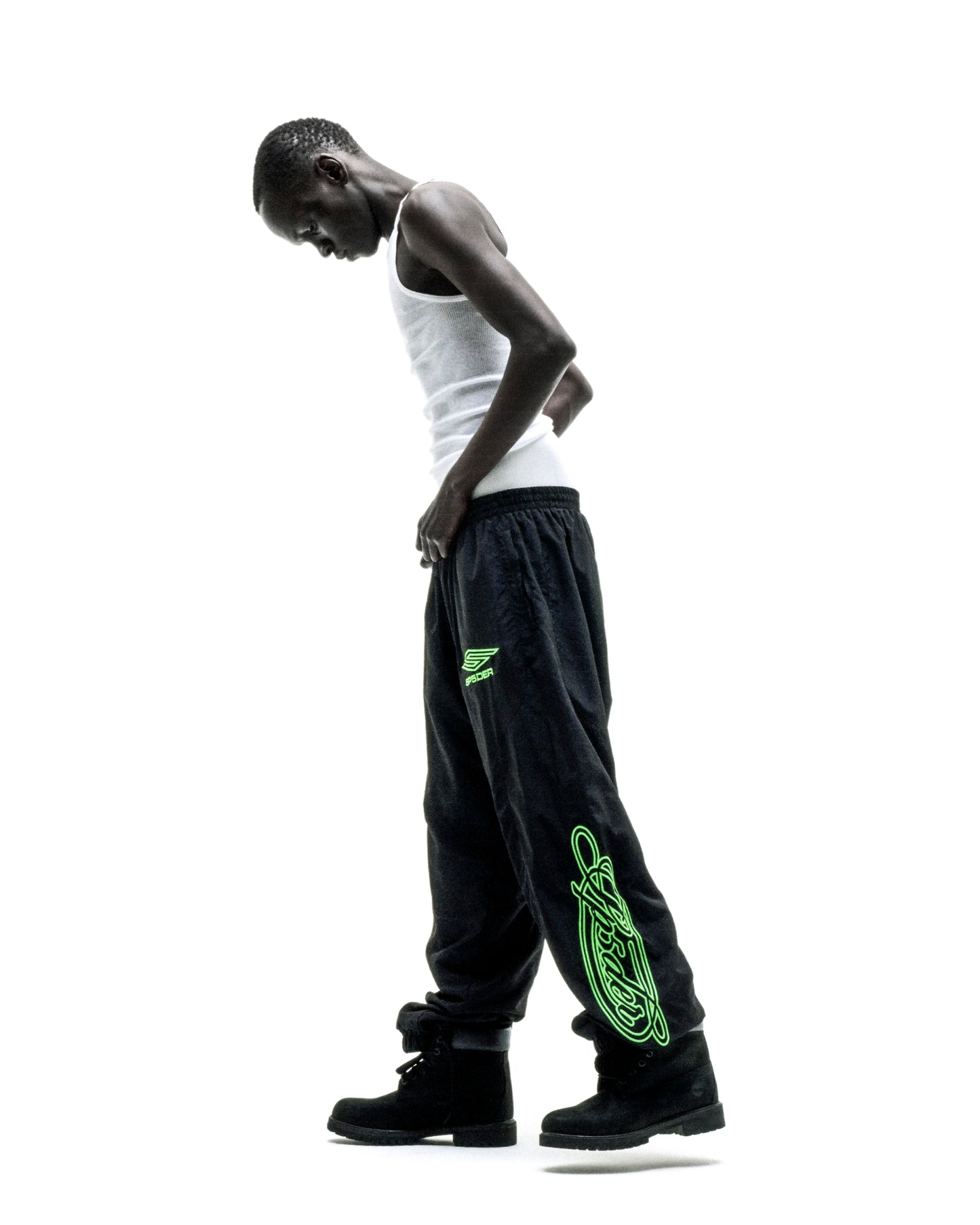 Black nylon track pant with neon green embroidered graphics, elastic cuffs, and paneled construction.