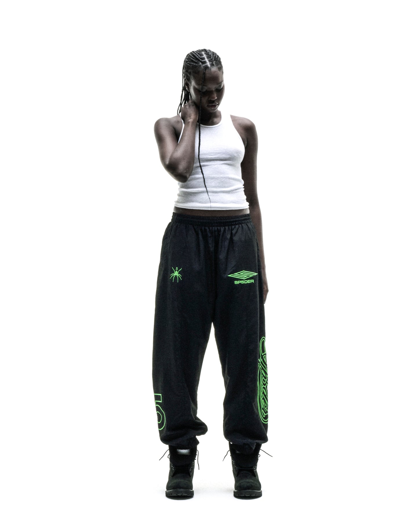Black nylon track pants with green embroidered graphics, elastic cuffs, and drawstring waist.