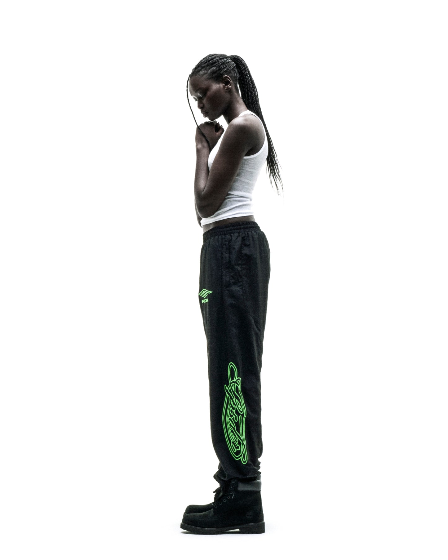 Black nylon track pants with green embroidered graphics and elastic cuffs.