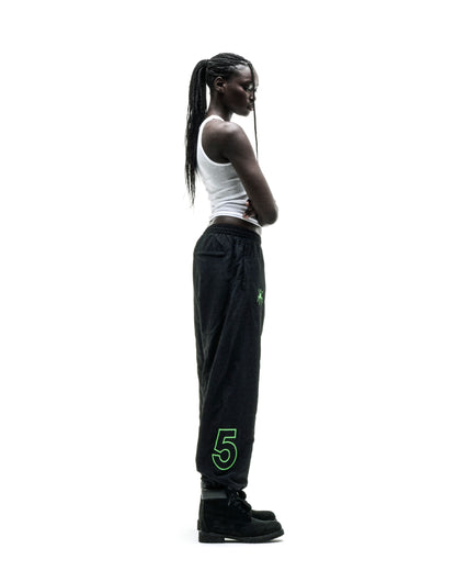 Black nylon track pant with green embroidered graphics and elasticized cuffs.