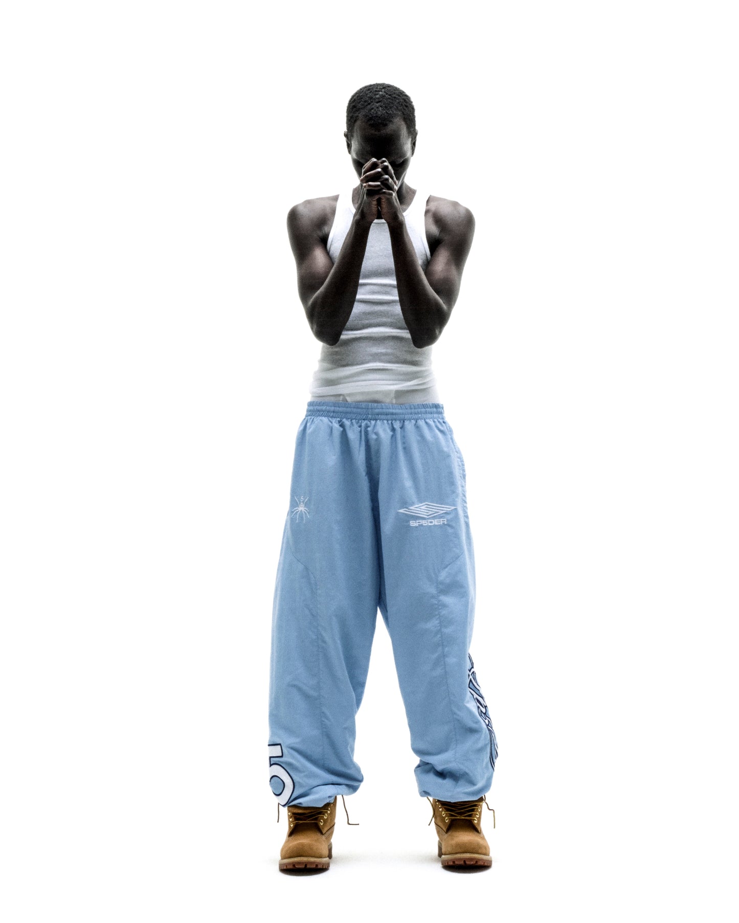 Light blue nylon track pants with embroidered graphics, paneled construction, and elastic cuffs.