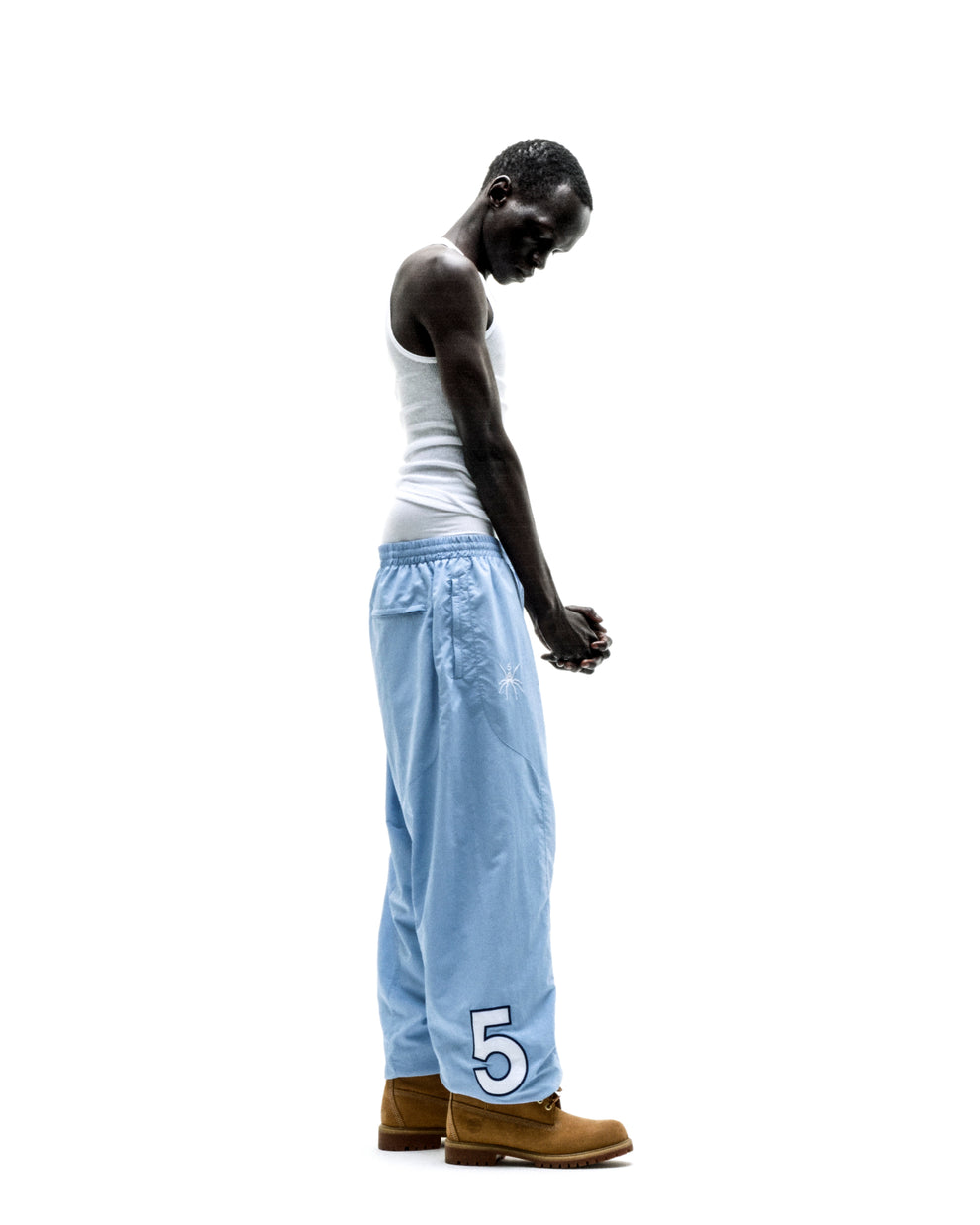 Light blue nylon track pant with embroidered graphic, paneled construction, and elastic cuffs.