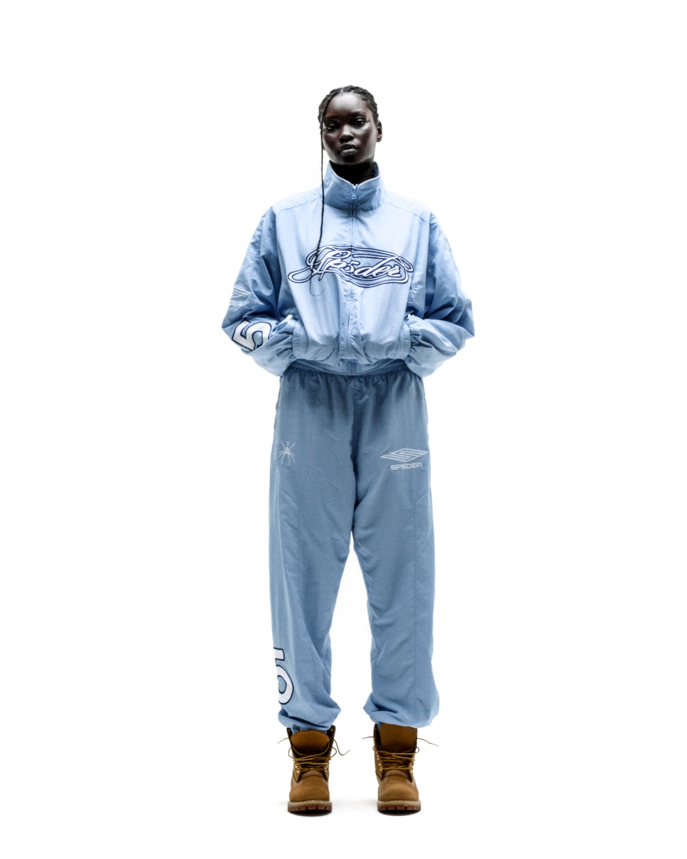Light blue nylon track jacket and matching pants with embroidered logos, worn by a model.