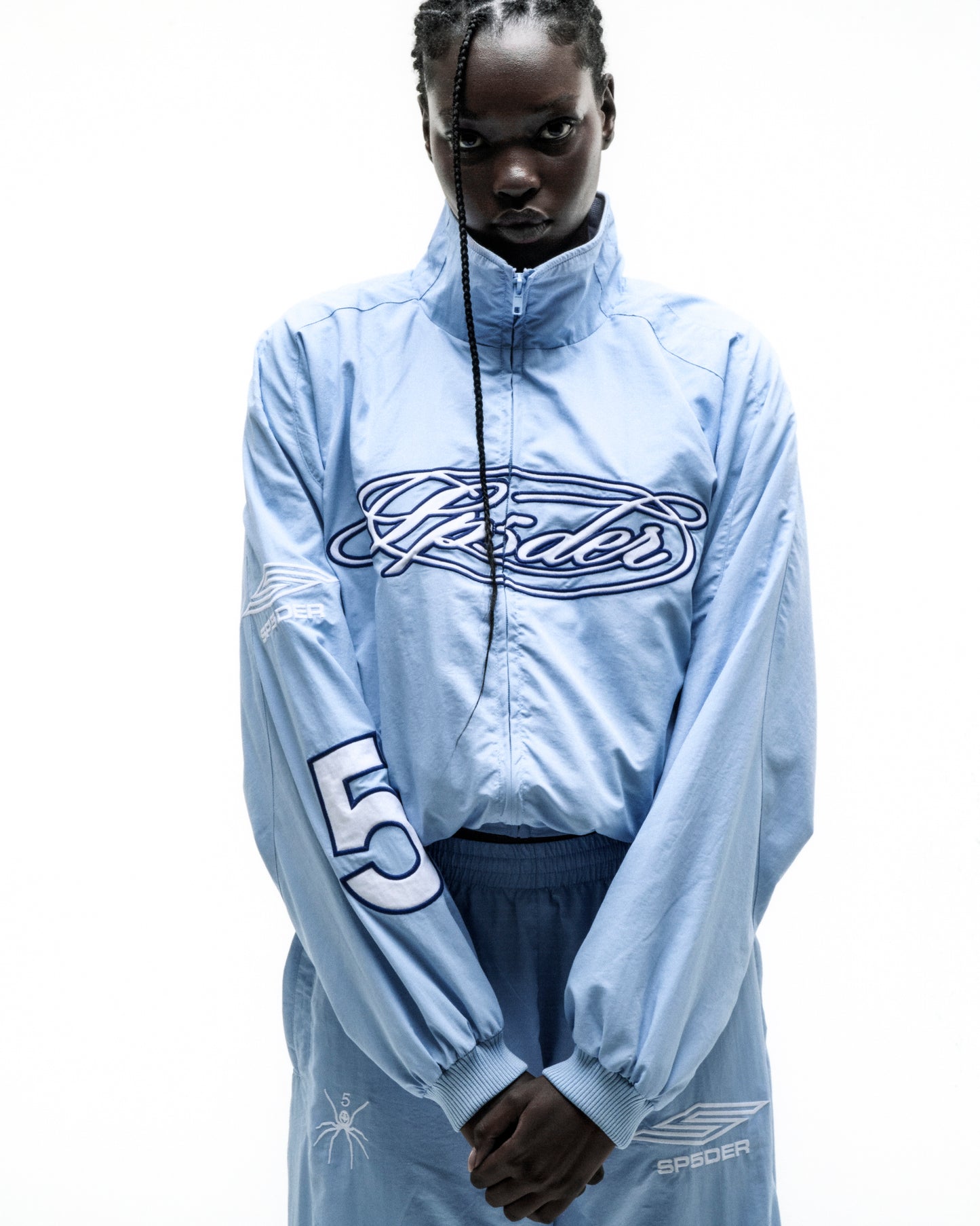 Light blue nylon track jacket with "Spider" chest logo, "5" on sleeve, stand collar, and elastic cuffs.