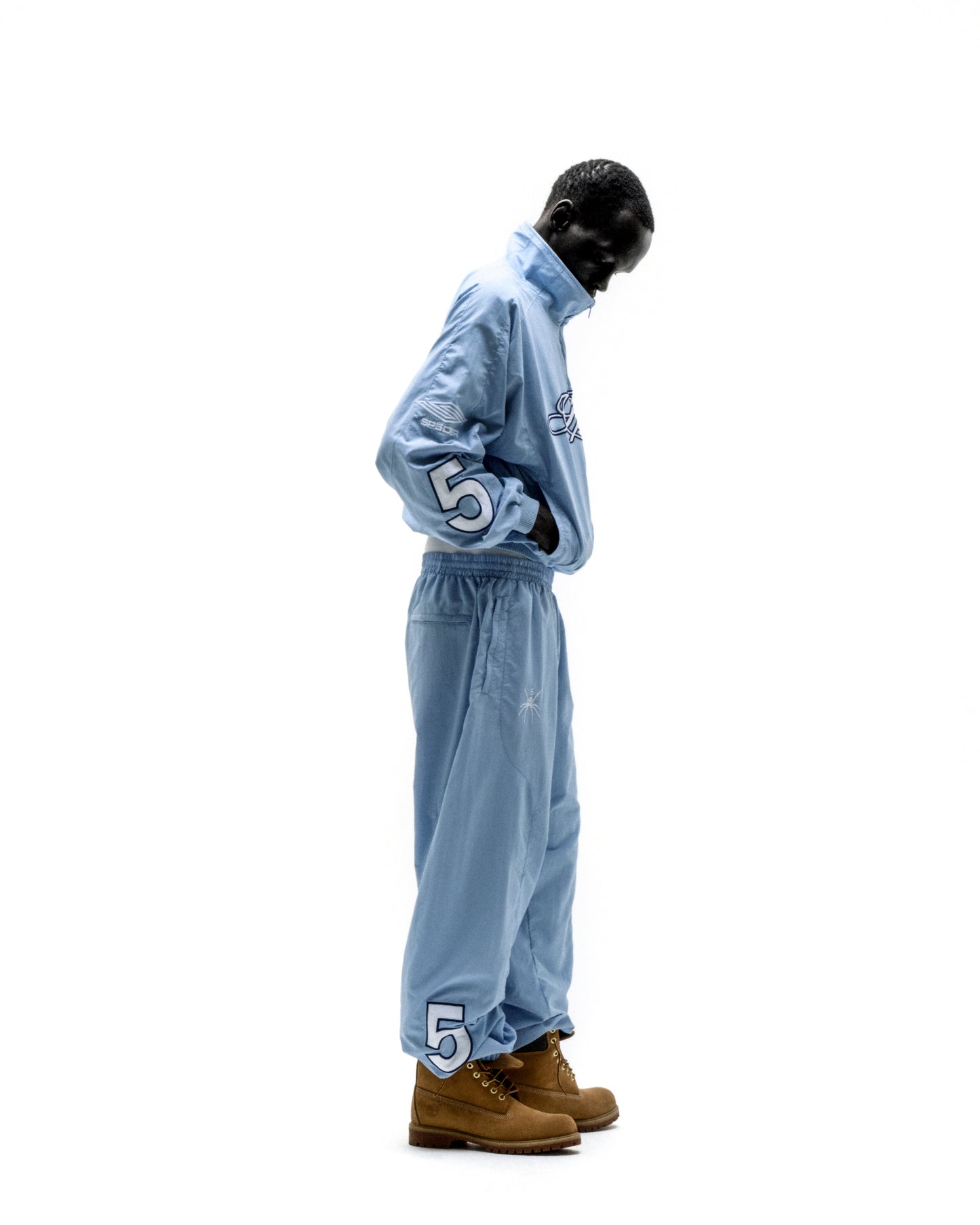 Light blue nylon track jacket and pants set with embroidered chest logo and "5" graphic on sleeves and pant legs.