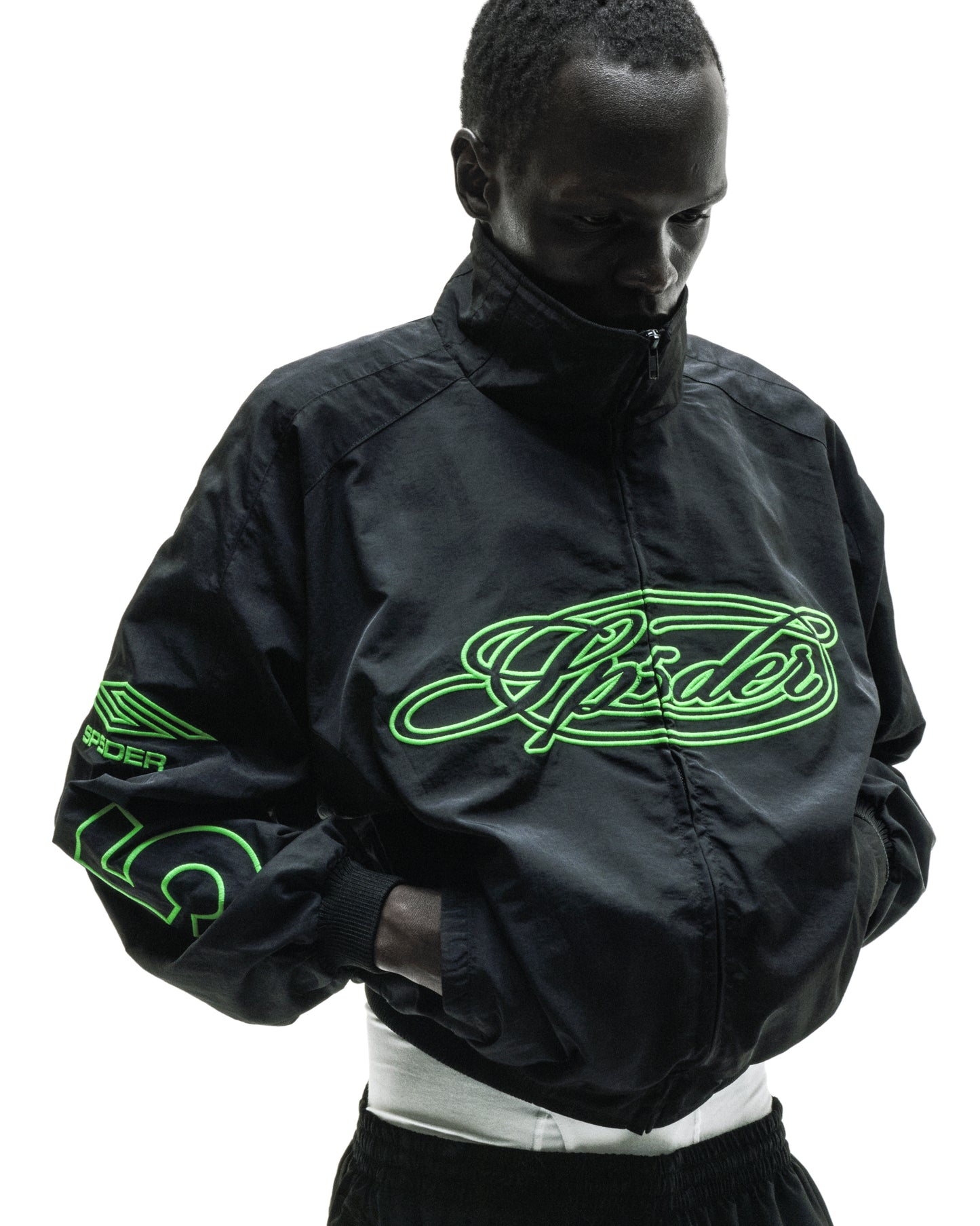 Black nylon track jacket with full zip, stand collar, and neon green embroidered "Spider" logo.