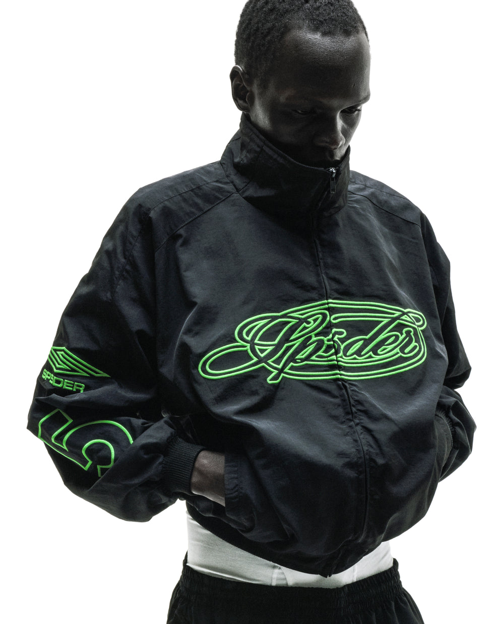 Black nylon track jacket with full zip, stand collar, and neon green embroidered "Spider" logo.