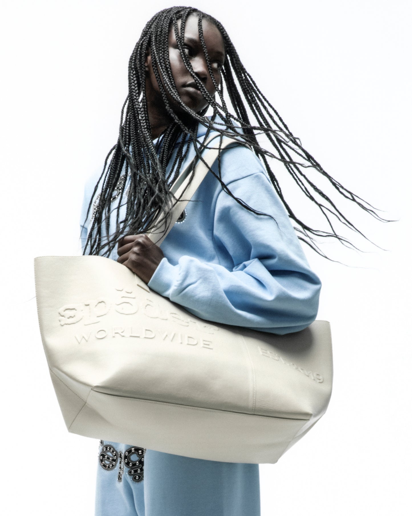 Off-white genuine leather tote bag with embossed logo, structured silhouette, and dual shoulder straps.