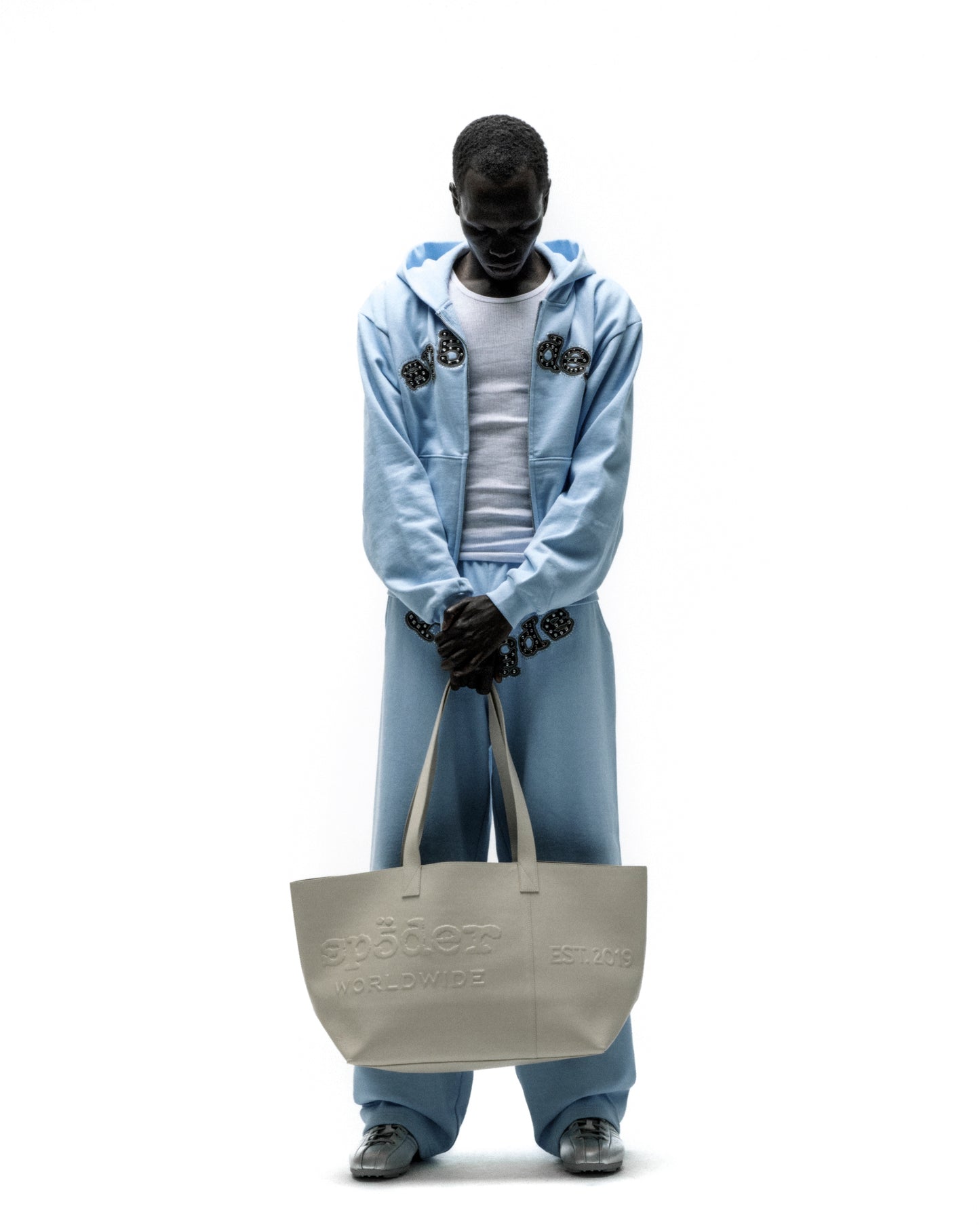 Light gray genuine leather tote bag with embossed "SP5DER WORLDWIDE" logo and "EST. 2019" detail.