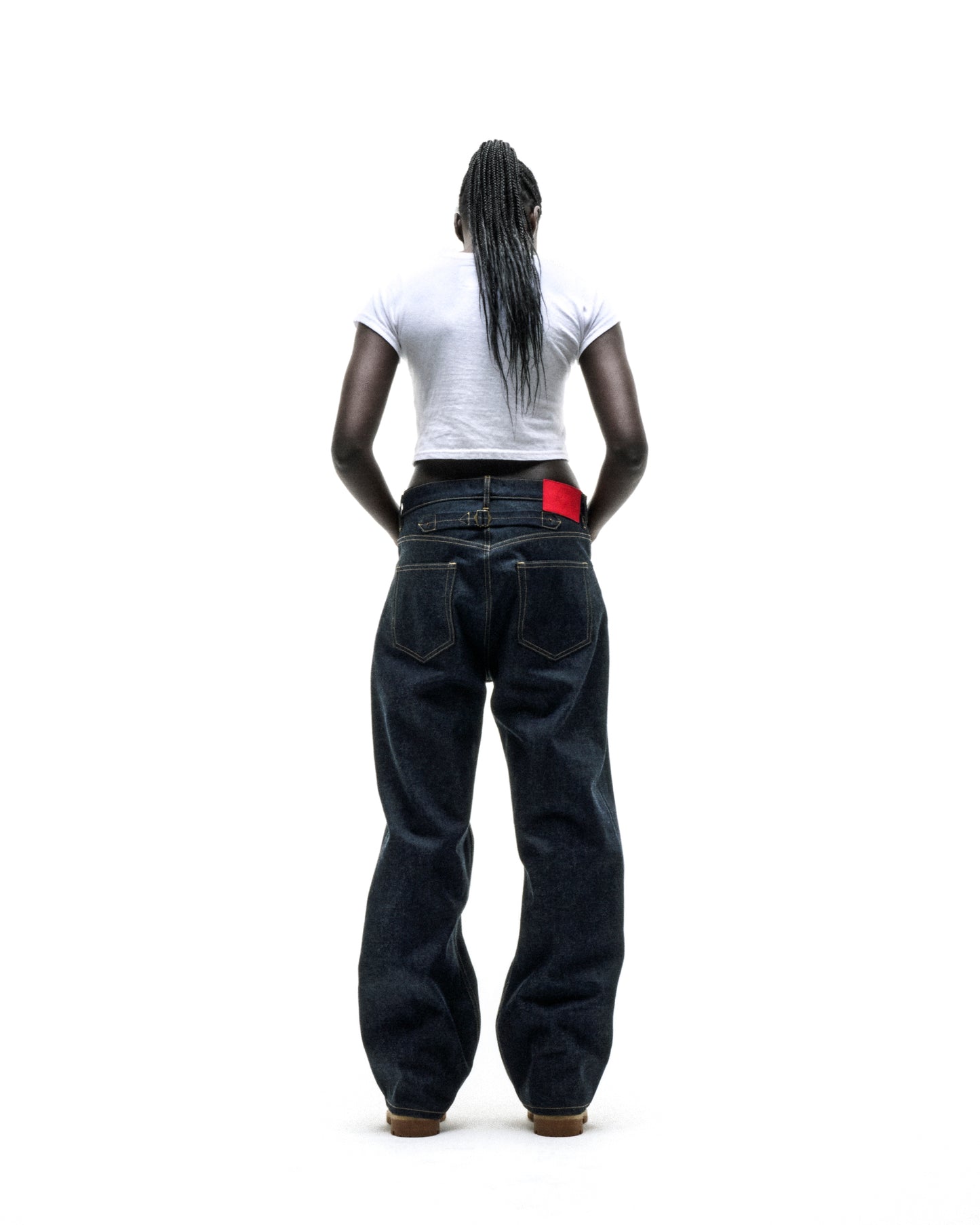 Woman from behind wearing a white cropped CUNTRY 5 BABY TEE and dark wash baggy jeans.