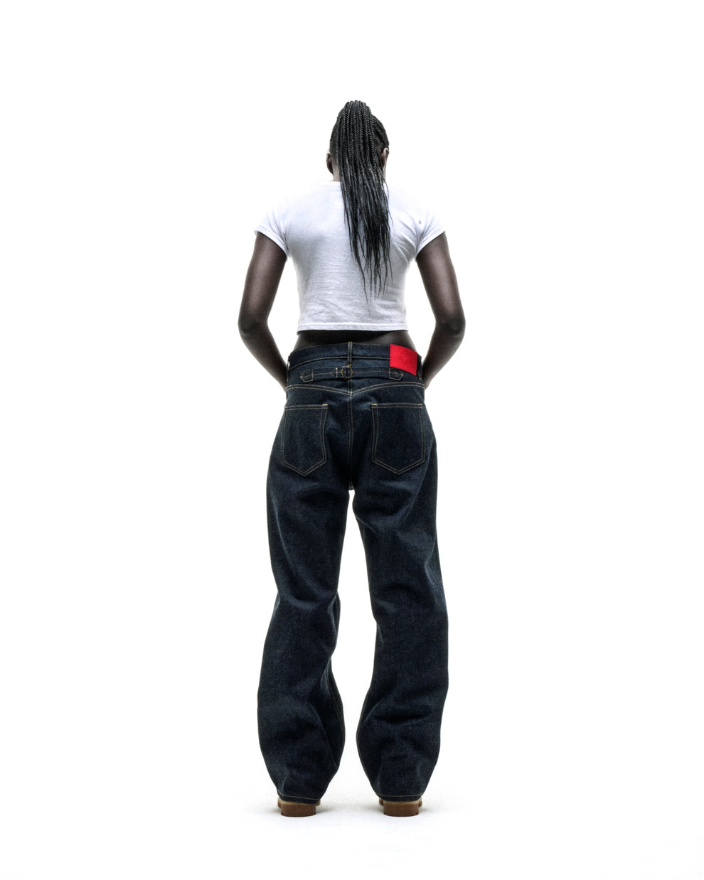 Woman from behind wearing a white cropped CUNTRY 5 BABY TEE and dark wash baggy jeans.