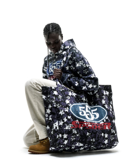 R5CING TOTE BAG: Dark blue star camo brushed twill tote with "555" logo, held by a model.