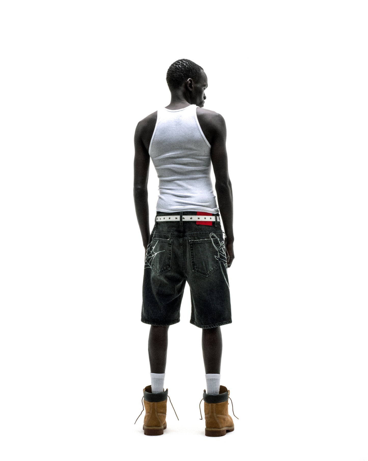 Dark wash denim shorts with rhinestone web design, belt loops, and five-pocket styling on a person.