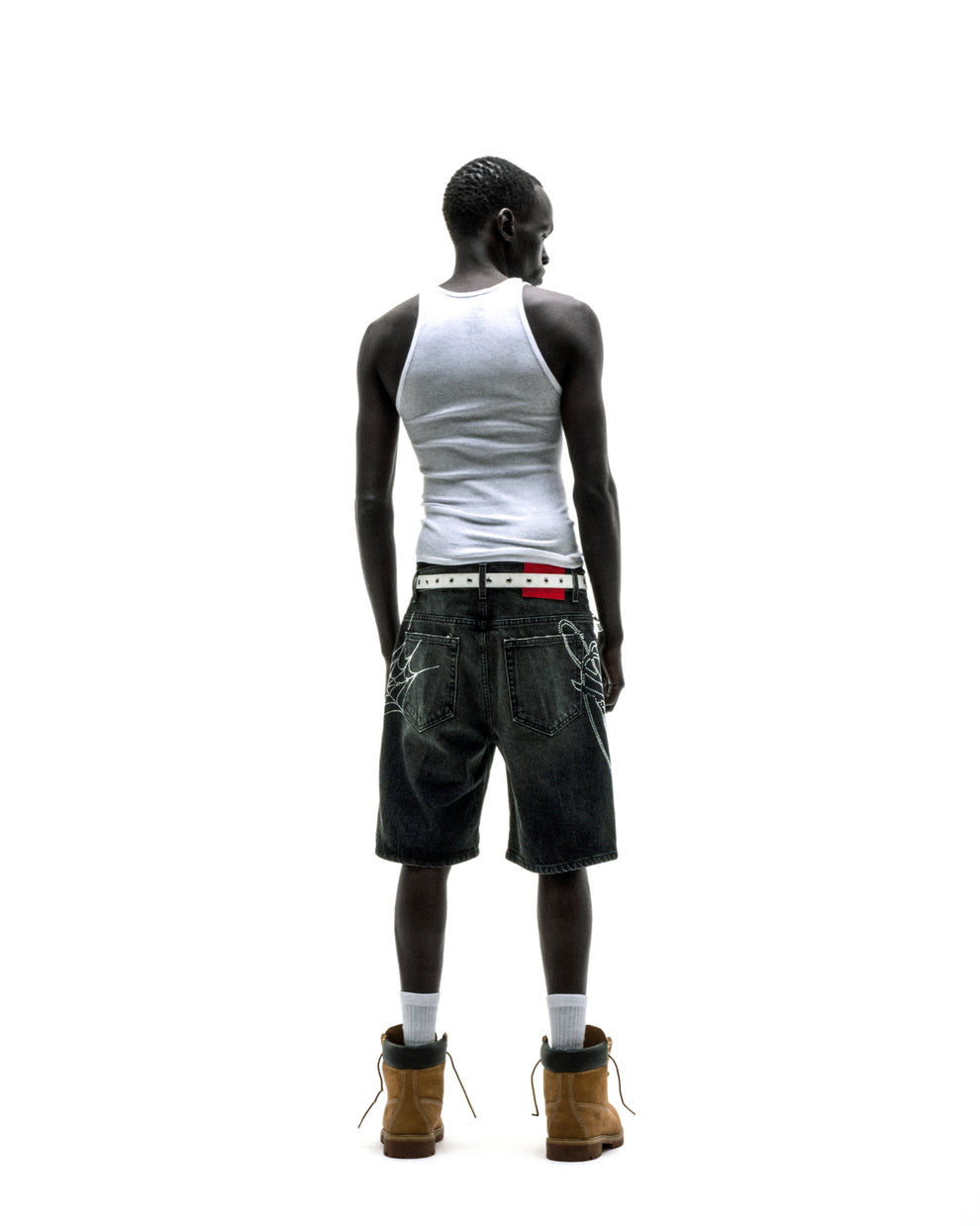 Dark wash denim shorts with rhinestone web design, belt loops, and five-pocket styling on a person.