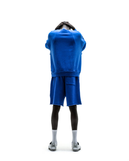 Blue crewneck sweatshirt paired with matching blue shorts, worn by a model viewed from the back.