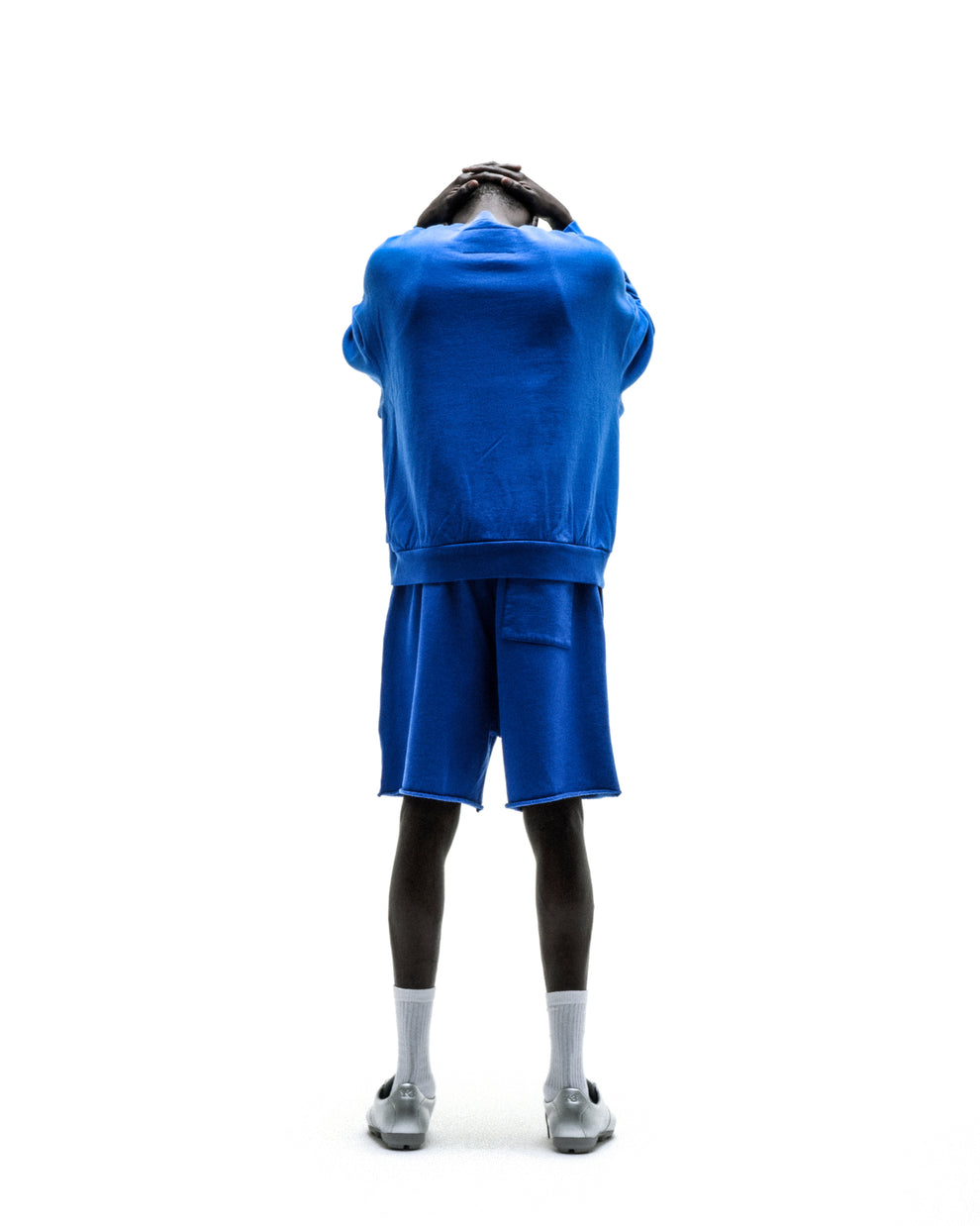 Blue crewneck sweatshirt paired with matching blue shorts, worn by a model viewed from the back.