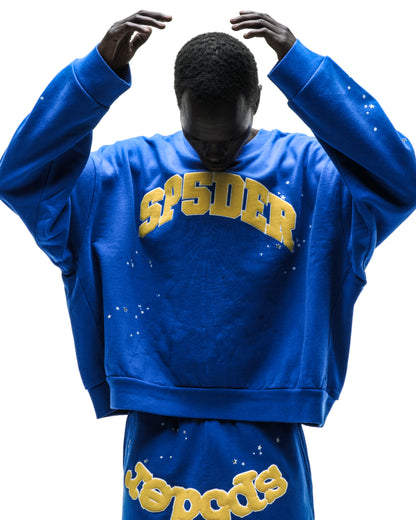 Blue oversized crewneck sweatshirt with yellow "SP5DER" text and white paint splatter details.