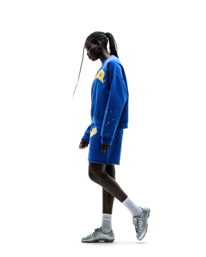 Blue crewneck sweatshirt with yellow varsity-style lettering on chest, paired with matching short.