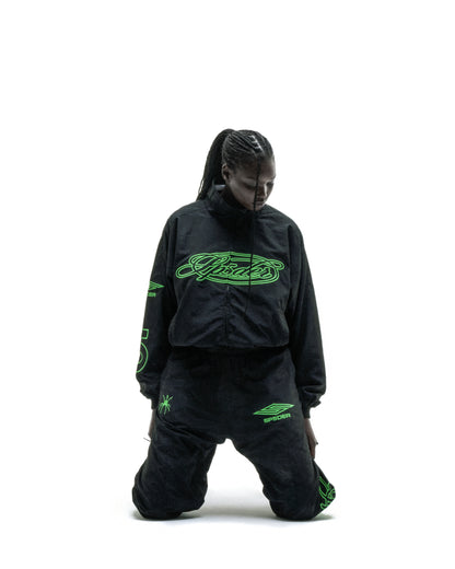 Black nylon track jacket with green embroidered chest logo, matching pants, and sleeve graphic.