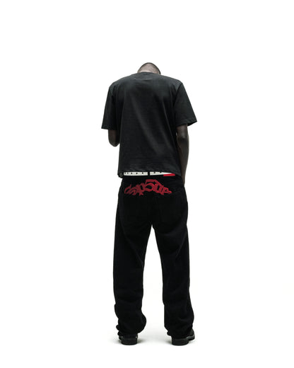 Man in black tee, black corduroy pants with red "Trapstar" embroidery, and a white belt.