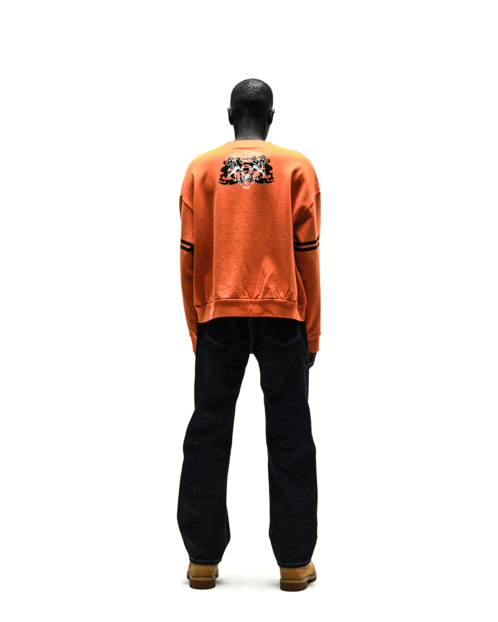 ARANEA CREWNECK: Orange crewneck sweatshirt with skull graphic on back, black arm stripes, dark jeans.