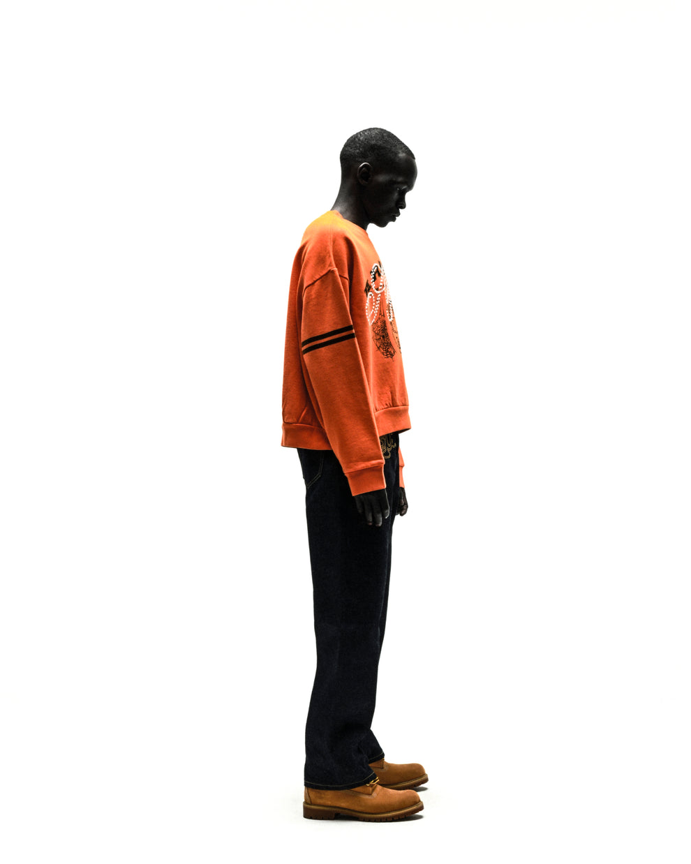 ARANEA CREWNECK: Orange oversized sweatshirt with black stripes on sleeve, worn by a dark-skinned model.