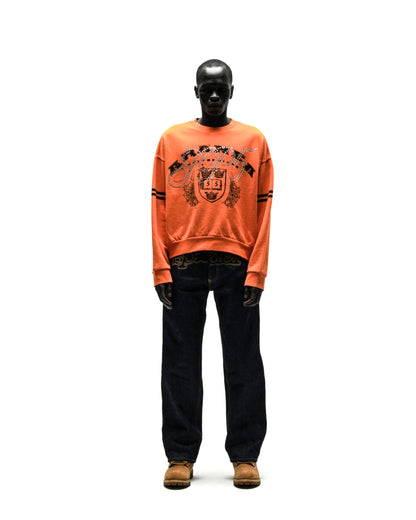 ARANEA CREWNECK: Orange oversized sweatshirt with black crest graphic, paired with dark wash jeans and brown boots.