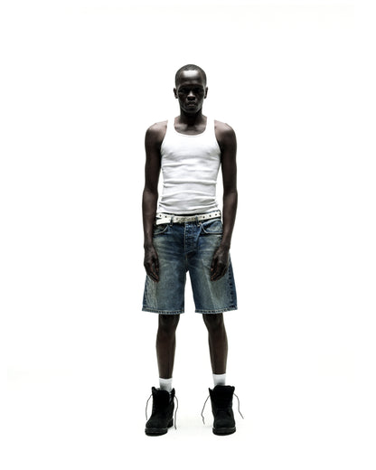Man wearing vintage wash denim shorts with rhinestone web design, a white tank top, and black boots.
