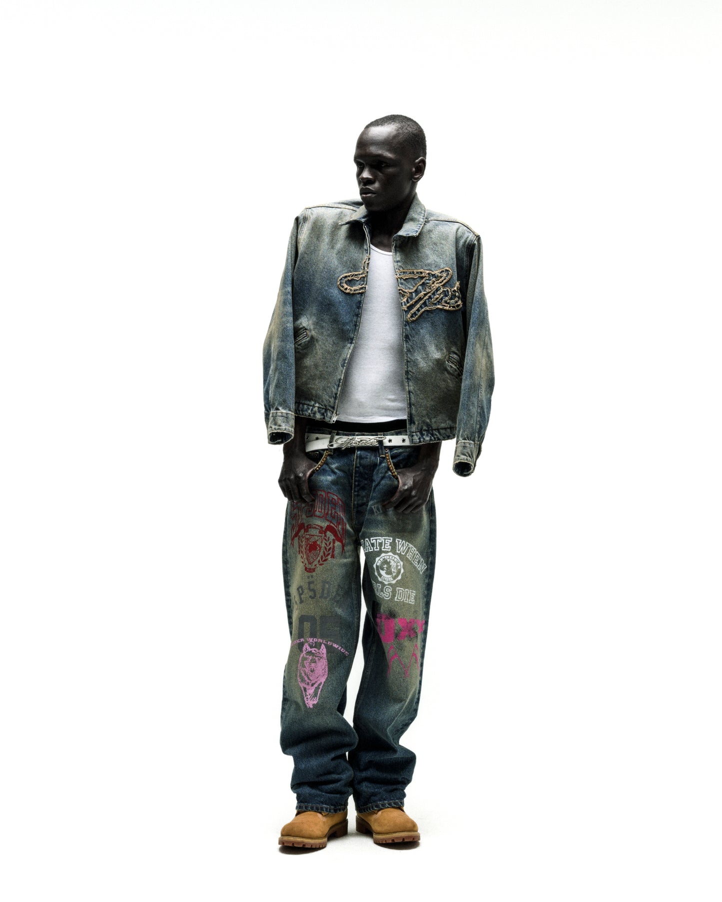 Worn blue denim work jacket with chain embroidery, paired with graphic jeans and a white tee.
