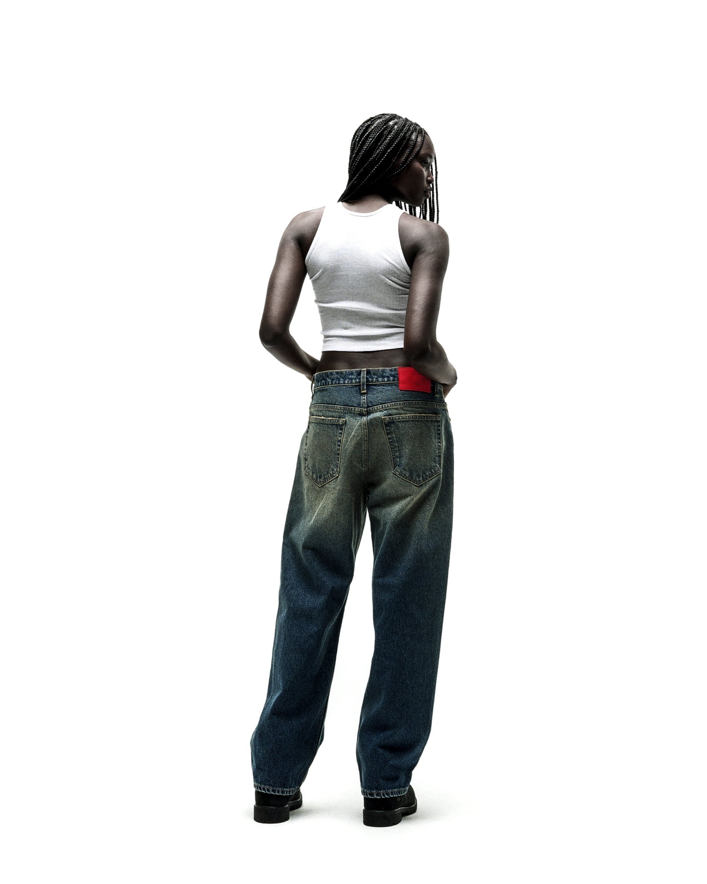 Woman in baggy, distressed blue jeans with a red waistband detail, viewed from behind.