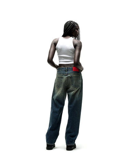 Woman in baggy, distressed blue jeans with a red waistband detail, viewed from behind.