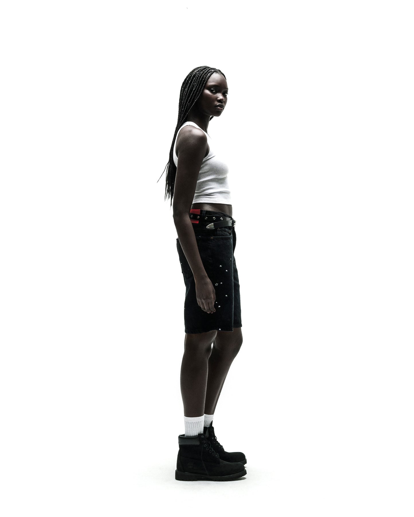 Black HEAVY WEB JEAN SHORTS with silver studs, worn by a model with a white tank top and black boots.