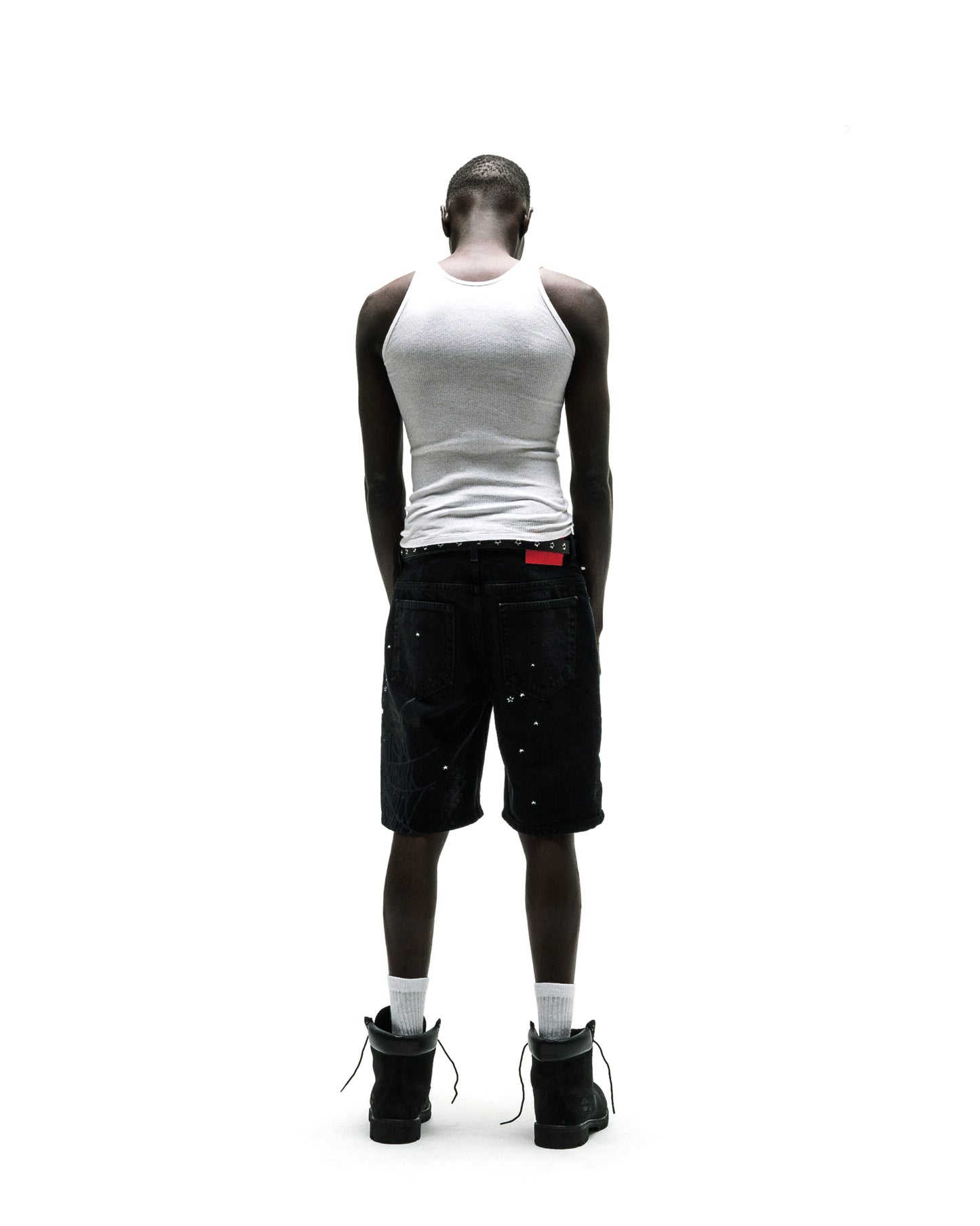 Black denim Heavy Web Jean Short with silver studs, red tag, and black boots.